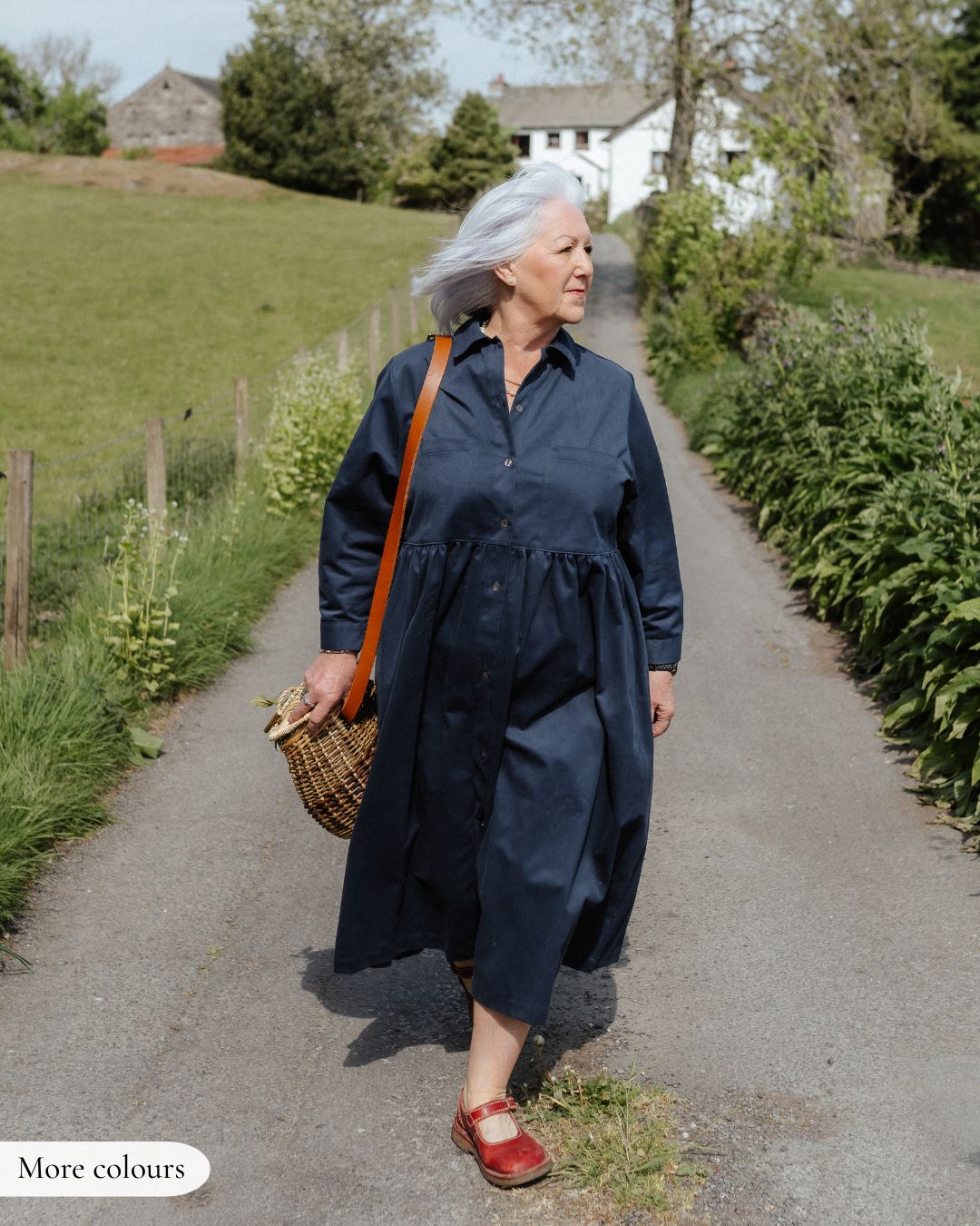 Woman in a blue dress walking along a path in a rural setting