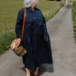 Woman in a  blue dress walking on a rural road with a basket.