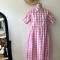 Pink and white checkered dress on a mannequin against a plain wall.