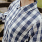 Person wearing a blue and white checkered shirt with a blurred background