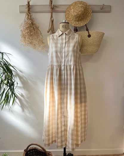 A long sleeve shirt dress with a checkered pattern, displayed on a hanger, featuring a collar and pic rac trim.
