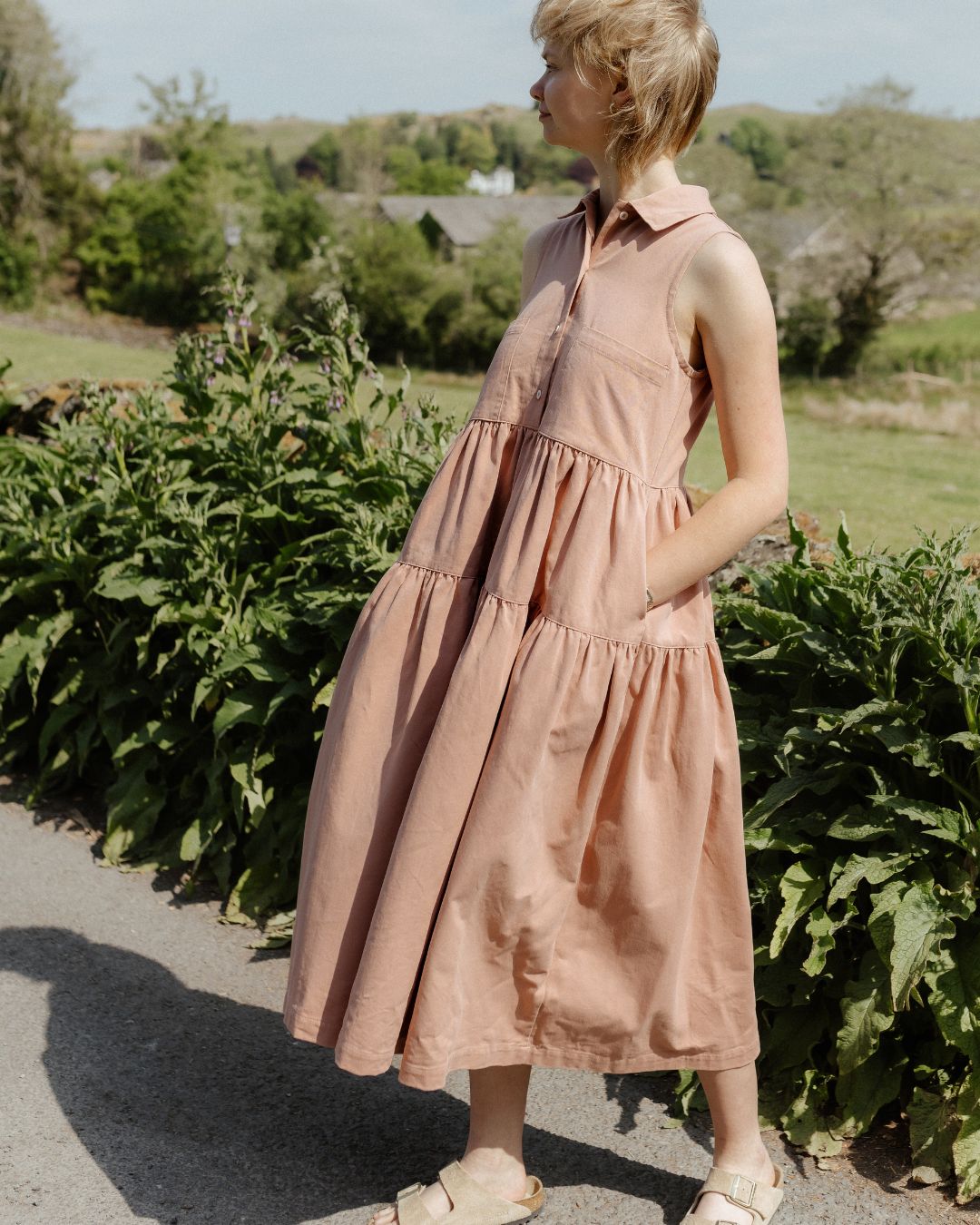 woman wearing pink sleeveless dress on country lane.