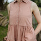 Cropped view of woman wearing sleeveless pink  dress with collar and 4 buttons to front