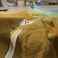 Close-up of a yellow fabric with a label on a sewing machine.
