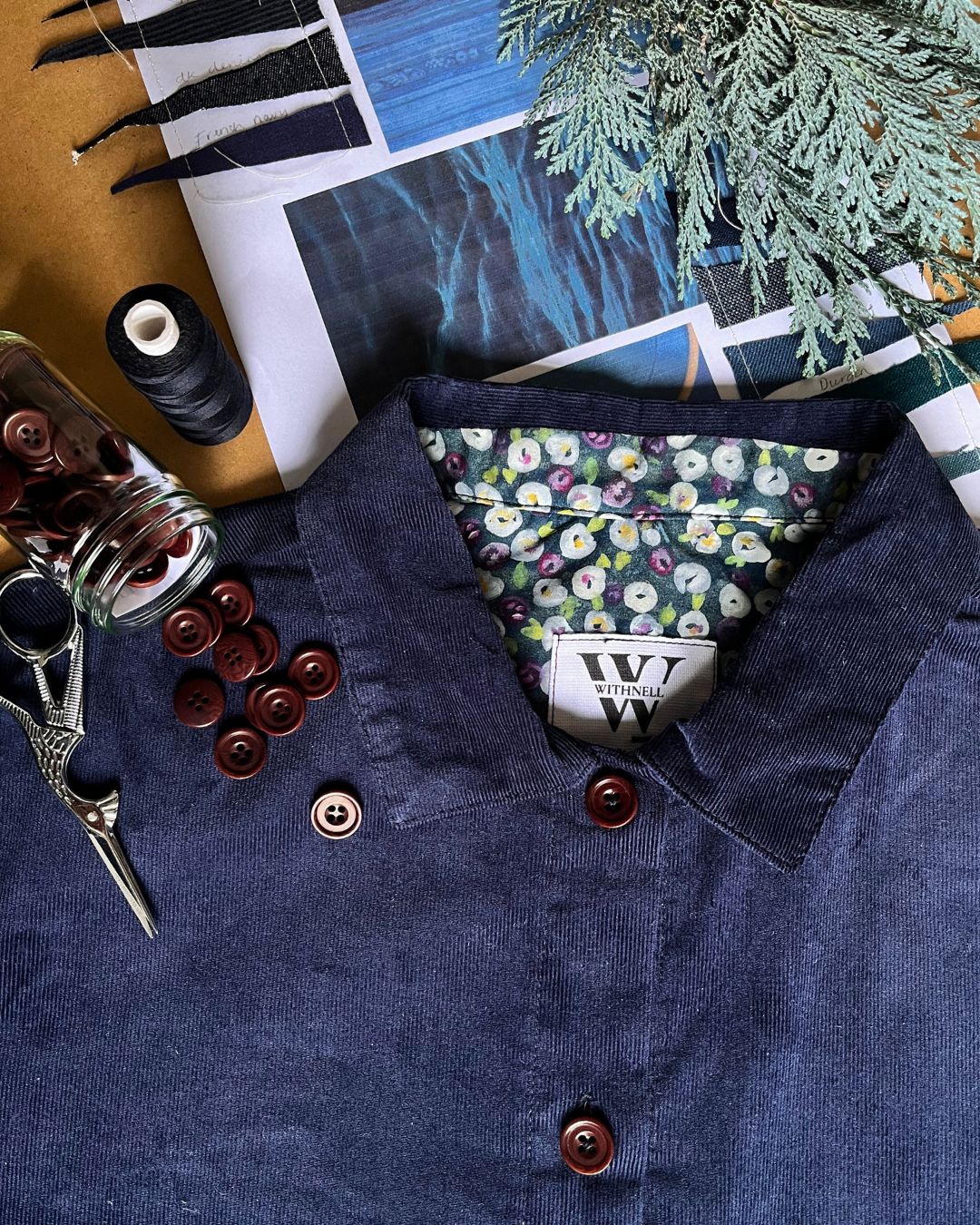 Close up detail of floral print inside a dress and on the collar. Buttons and scissors decorate.