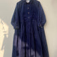 Navy blue dress on a hanger against a white wall