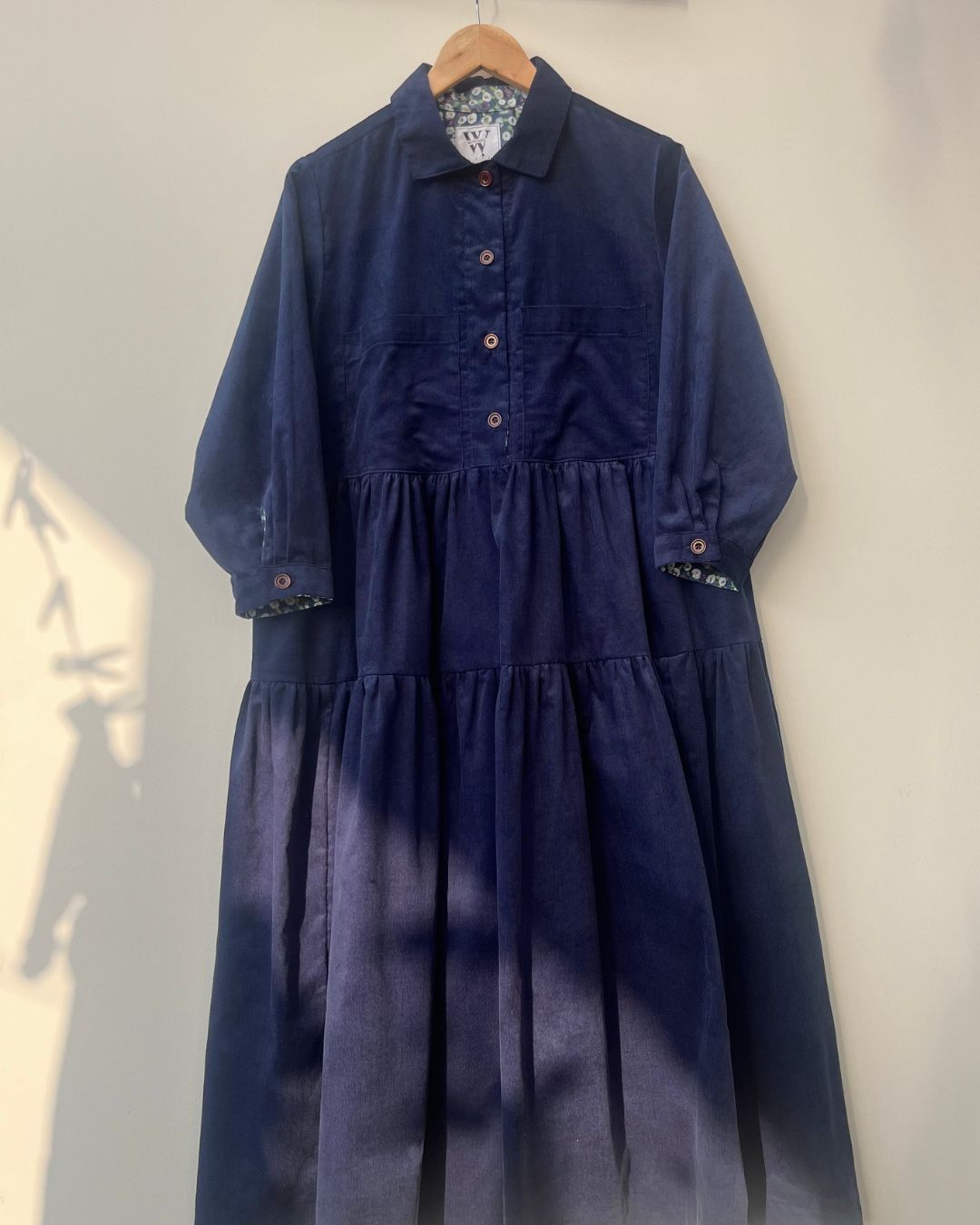 Navy blue dress on a hanger against a white wall