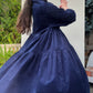 Model twirling in long tiered navy dress.