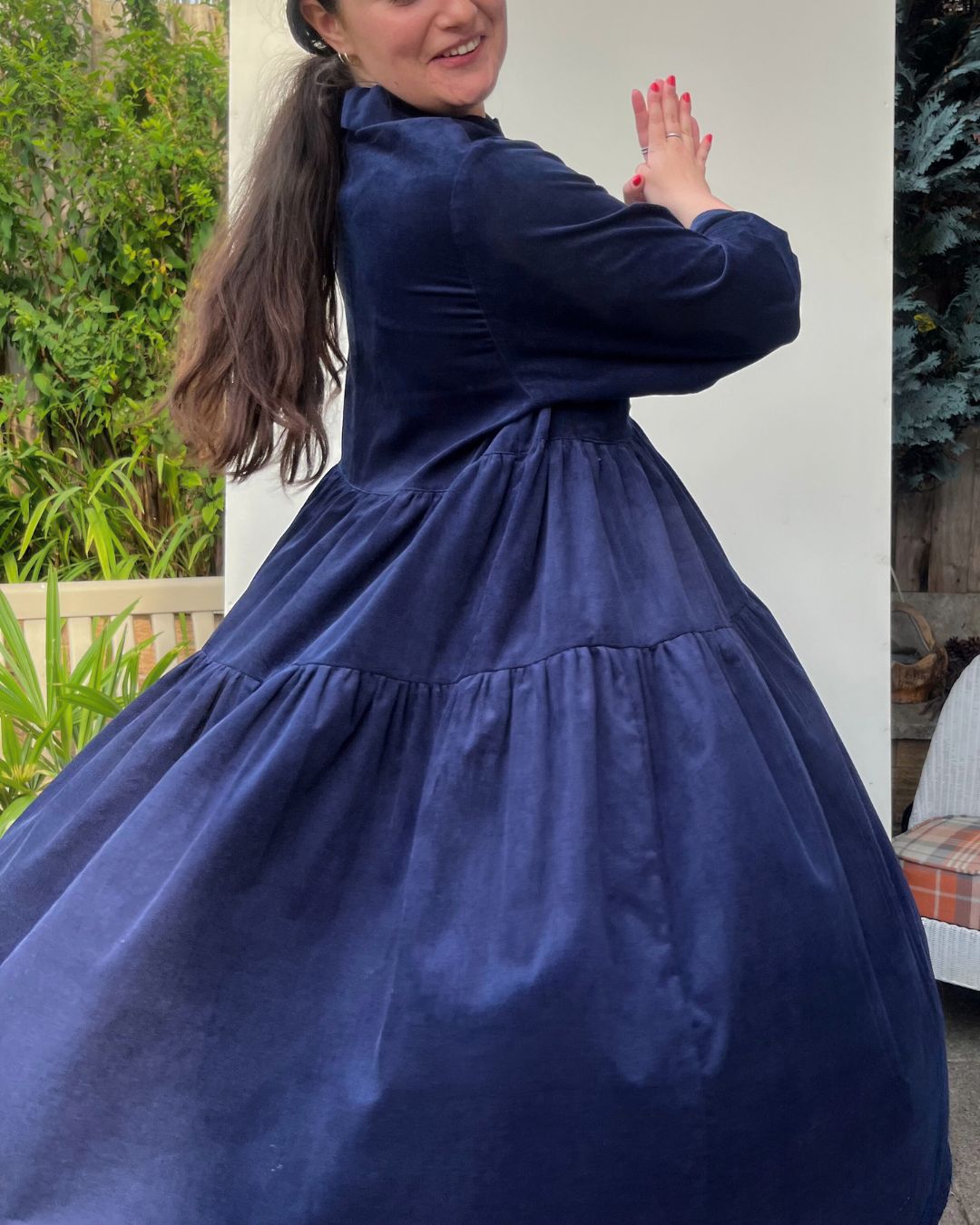Model twirling in long tiered navy dress.