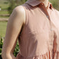 Person wearing a sleeveless pink dress with a blurred natural background