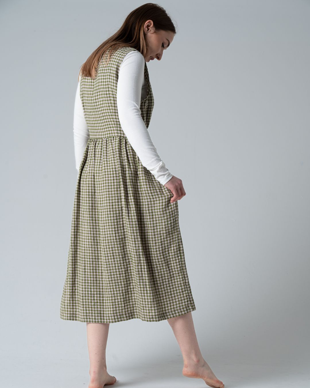 Woman wearing a green checkered dress against a plain background