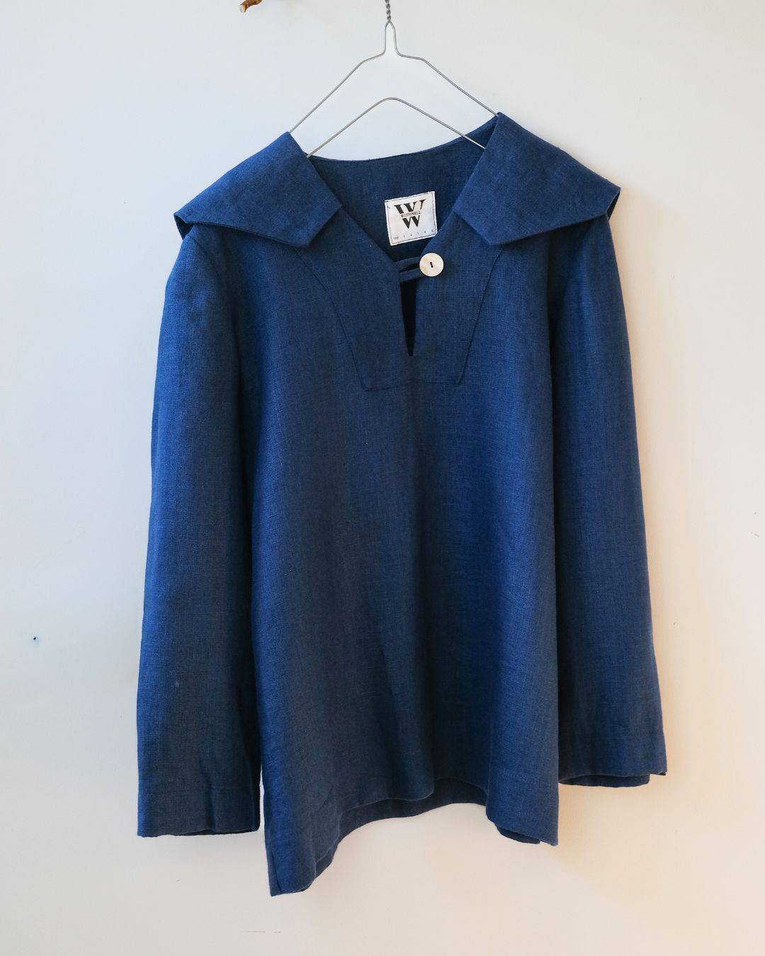 Blue sweater with a collar on a hanger against a white background