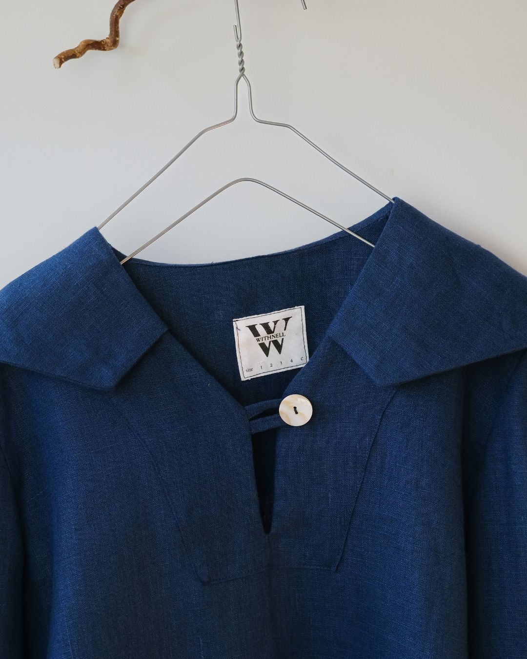 Blue shirt with a brand label on a hanger against a white background