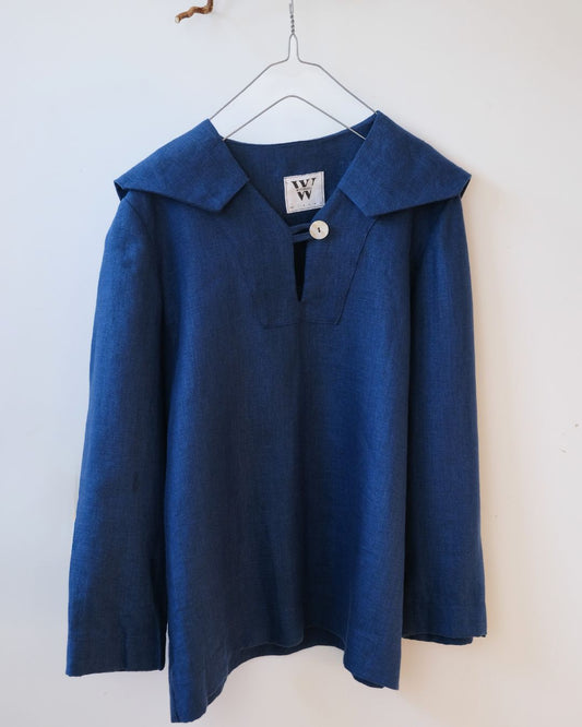 Blue shirt with a sailor collar on a hanger against a white wall