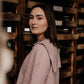 Woman in a pink coat standing among wooden crates