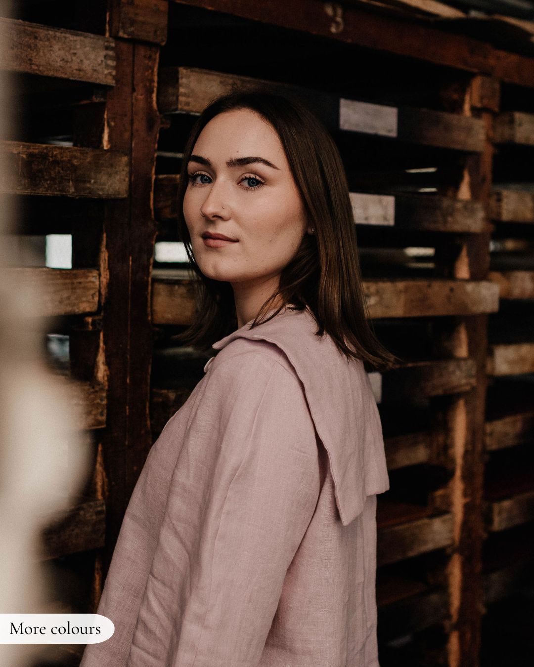 Woman in a pink coat standing among wooden crates