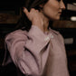 Woman wearing a light pink shirt with rolled-up sleeves in a dimly lit setting