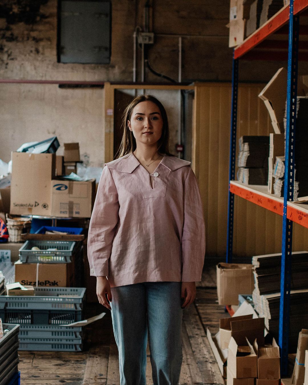 Woman standing in a warehouse with shelves and boxes in the background