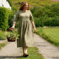 Woman walking with basket of flowers  in countryside.