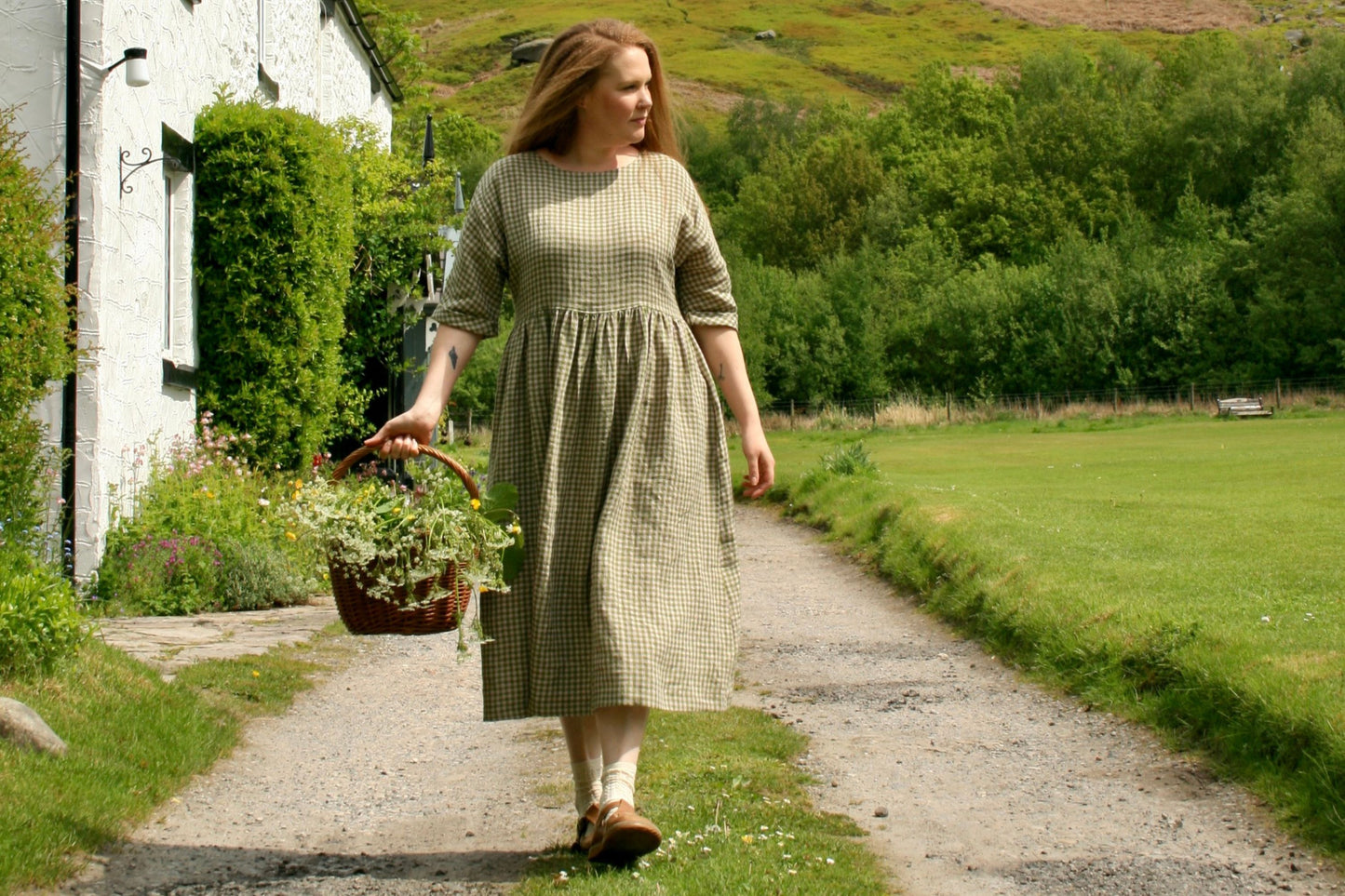 Woman walking with basket of flowers  in countryside.