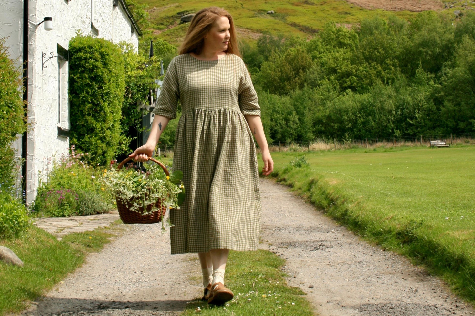 Woman walking with basket of flowers  in countryside.