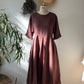 Brown dress on a mannequin against a white wall with decorative elements.