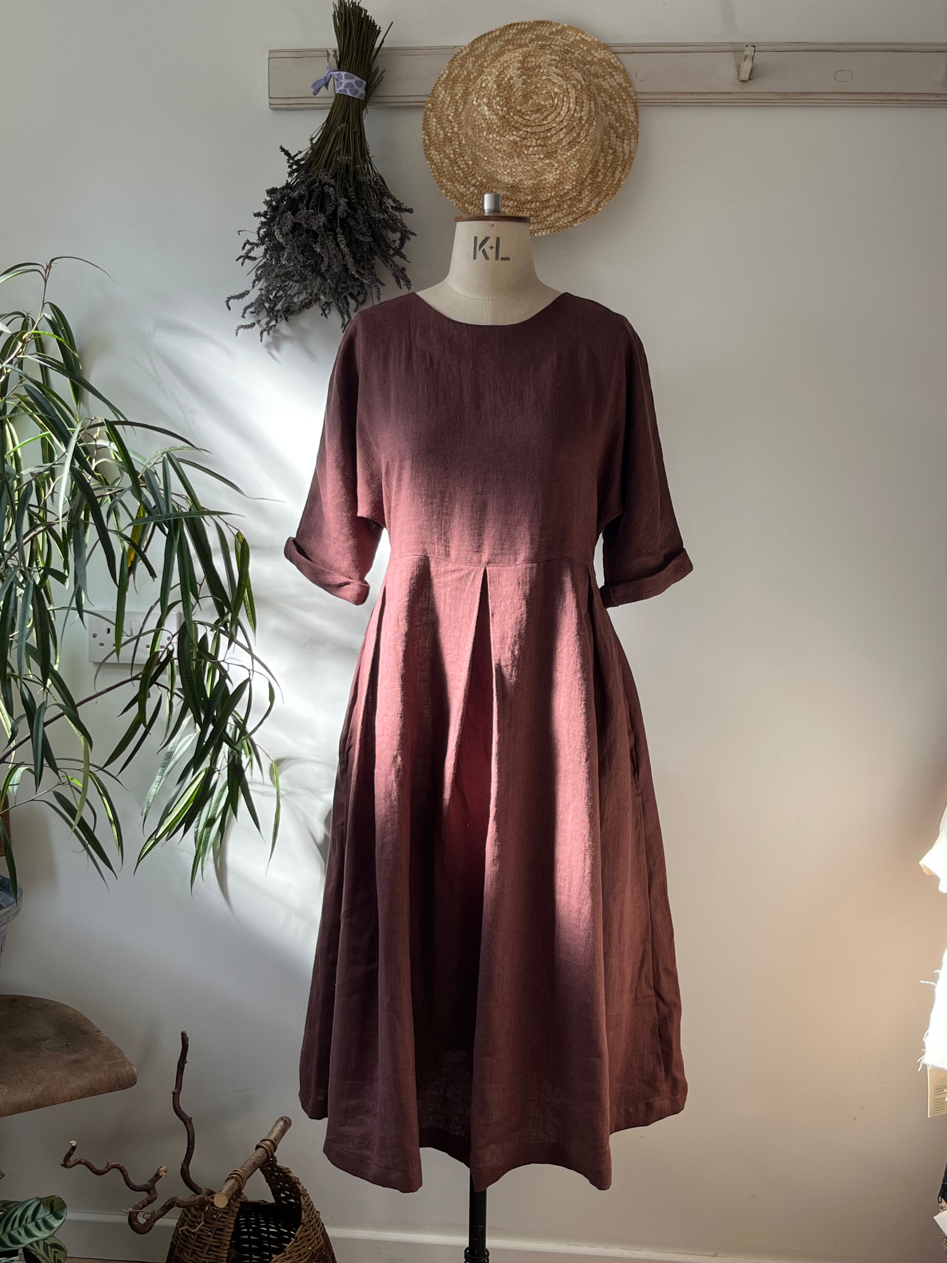 Brown dress on a mannequin against a white wall with decorative elements.
