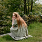 Woman with long red hair sitting on a grassy path in a natural setting