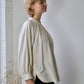 personn standing against war showing side view of white long sleeve blouse