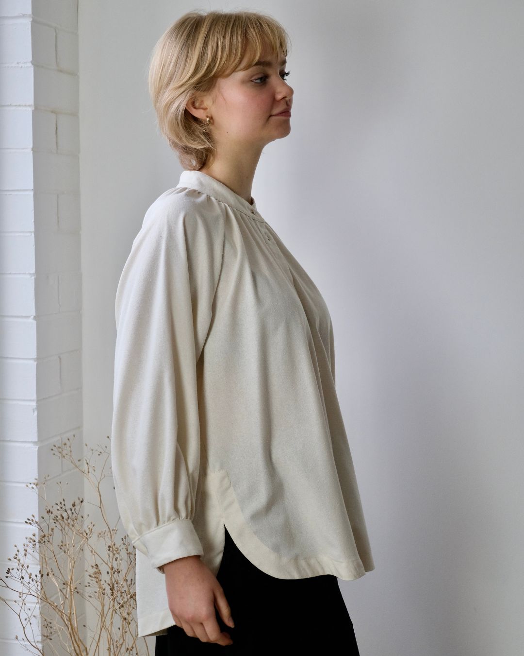 personn standing against war showing side view of white long sleeve blouse