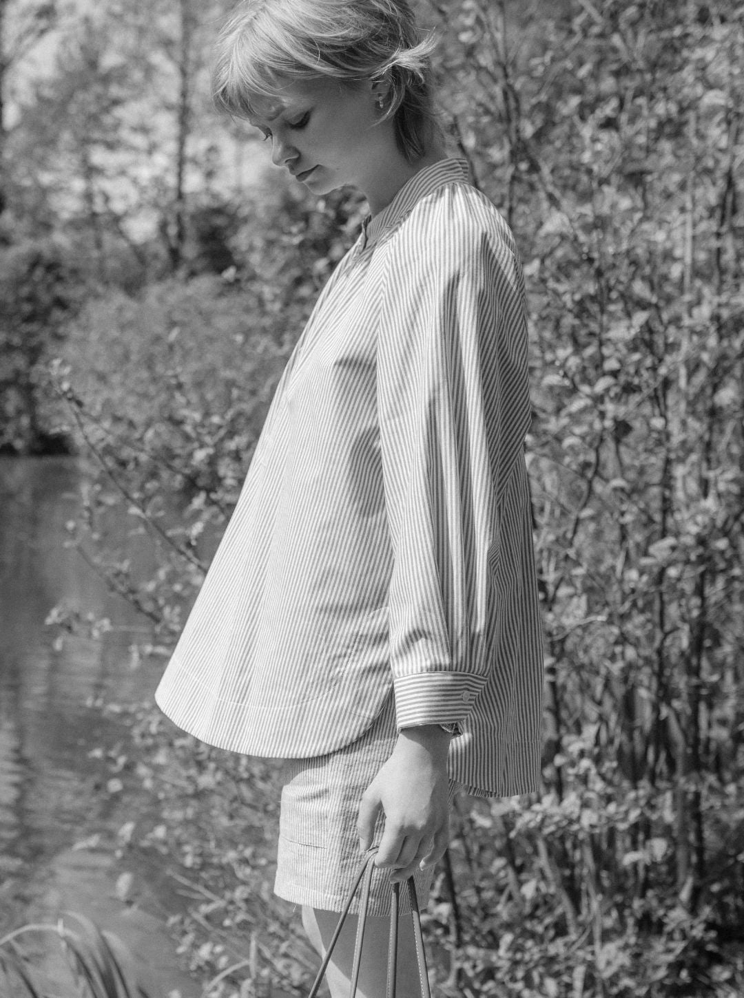 Woman in a striped outfit standing outdoors with trees in the background