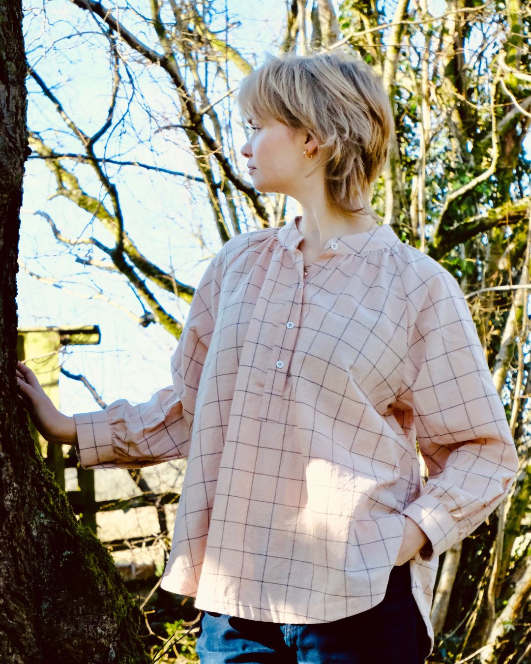Person wearing a plaid shirt standing in a forest
