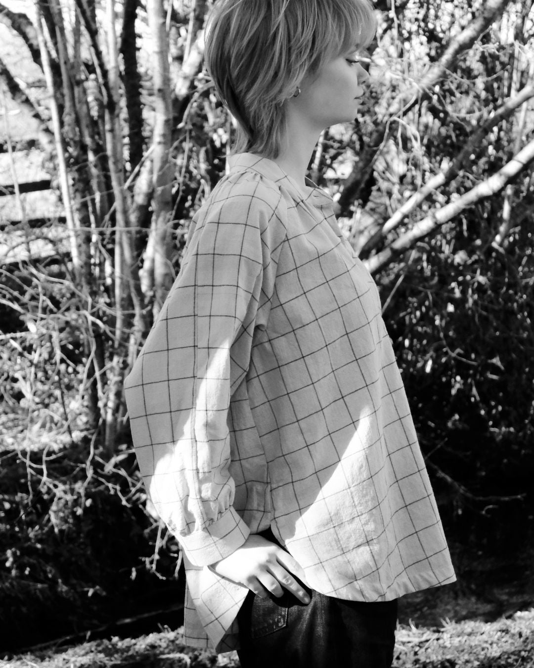 Person wearing a checkered shirt in a natural setting