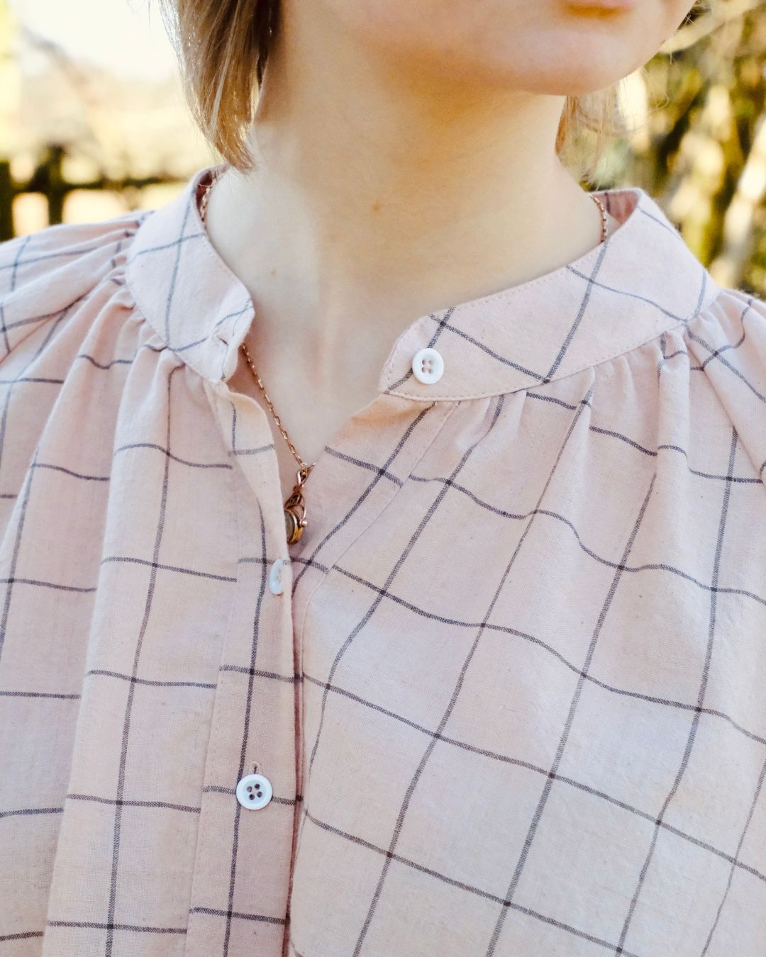 Close-up of a person wearing a plaid shirt with a blurred background