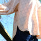 Person wearing a checkered shirt with a blurred outdoor background