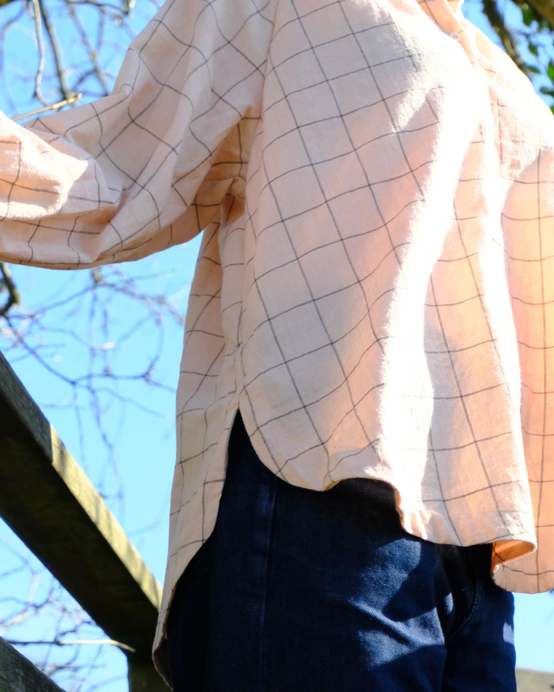 Person wearing a checkered shirt with a blurred outdoor background