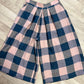 Plaid pants with pink and blue check pattern on a wooden floor.