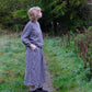 Person wearing a checkered dress standing on a path in a natural setting