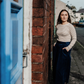 a person stood outside a blue door on a street wearing stripe top and blue cord culottes