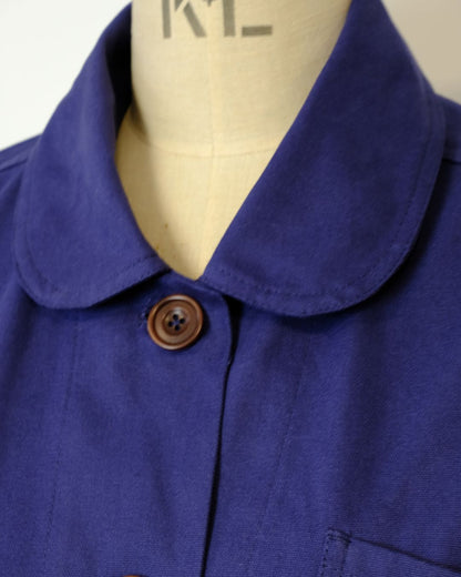 Close-up of a blue garment with a brown button on a mannequin.