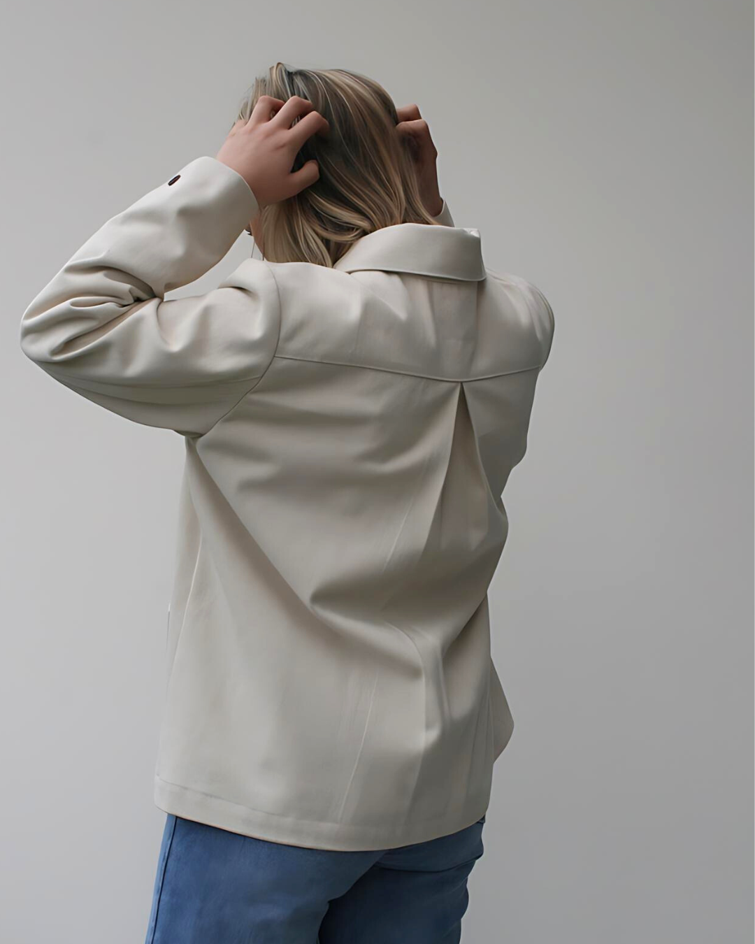 person wearing cream coloured jacket showing back view with white background