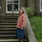 woman standing on steps wearing a pink jacket.