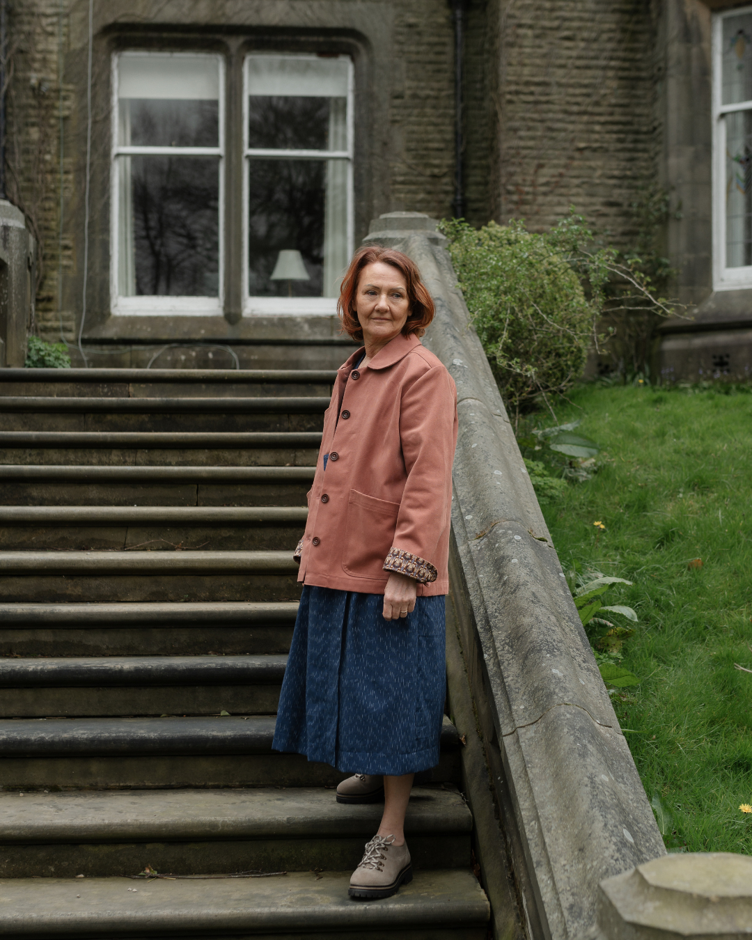 woman standing on steps wearing a pink jacket.
