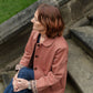 woman sitting on steps outside wearing pink jacket
