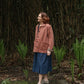 woman standing in garden wearing pink jacket.