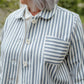 Person wearing a blue and white striped shirt with a pocket outdoors.