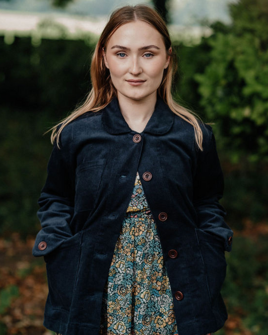woman standing wearing navy corduroy jacket in woodland setting
