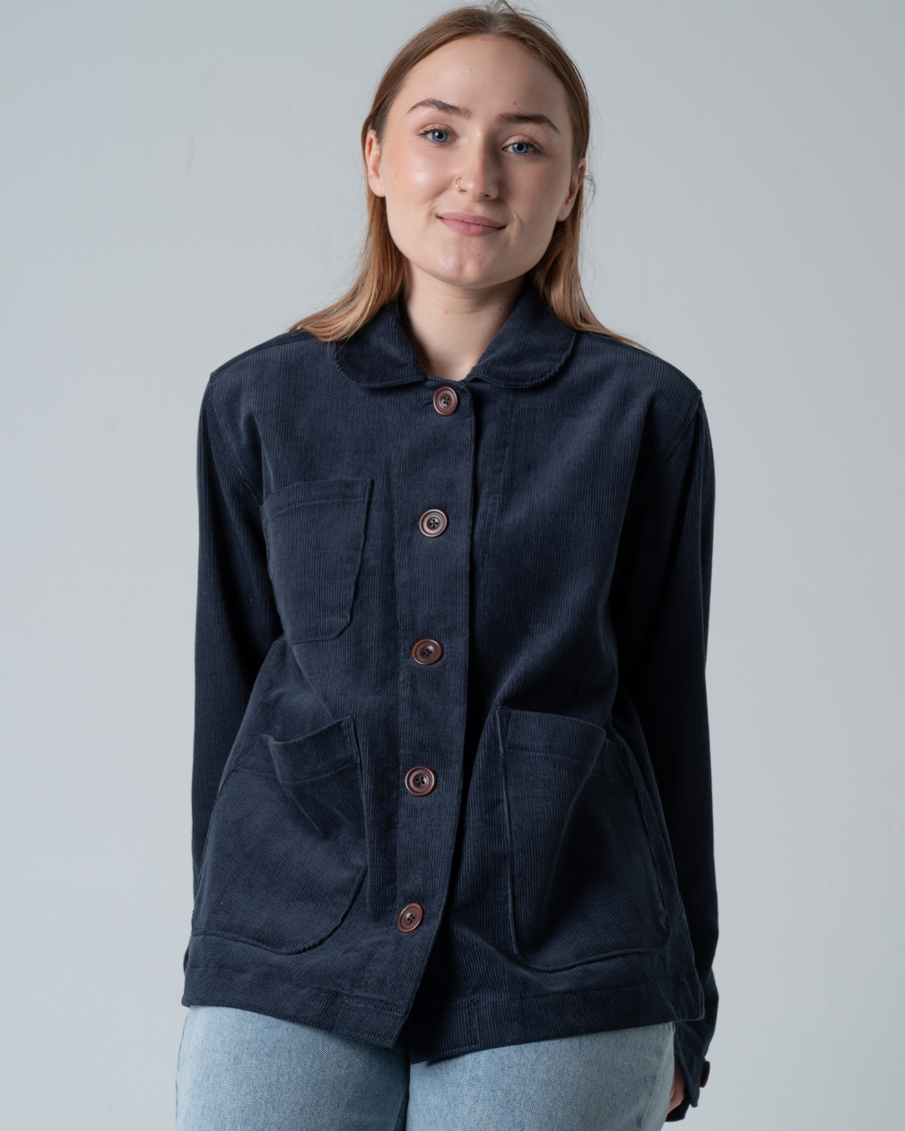 woman sitting with grey background wearing corduroy jacket in blue