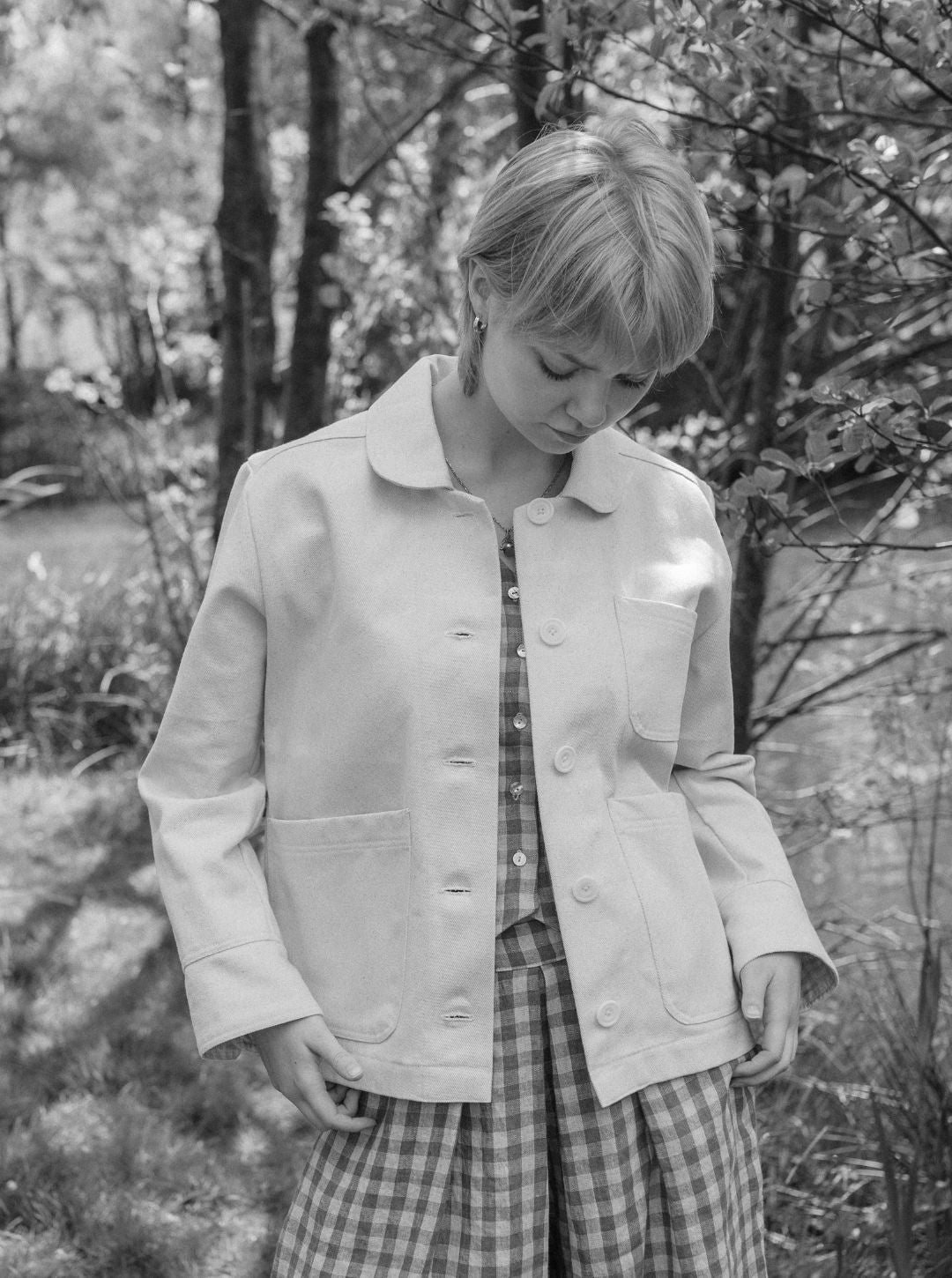 Person wearing a light-colored jacket and plaid pants in a natural setting