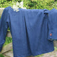 Blue jacket draped over a wooden fence with greenery in the background